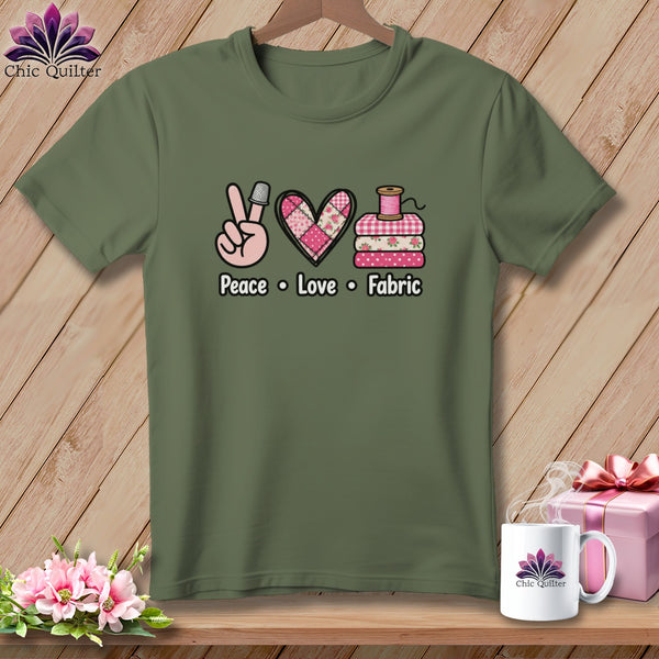 Olive green t-shirt with a Peace, Love, Fabric graphic featuring a thimble, heart, and folded fabrics.