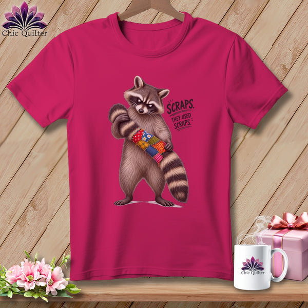 Raccoon holding a patchwork tube with text "SCRAPS. THEY USED SCRAPS."