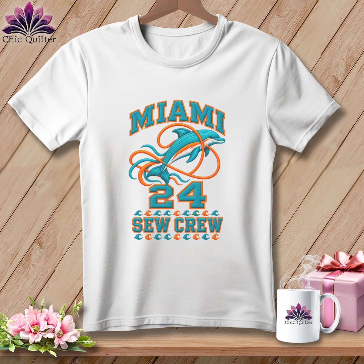 A white t-shirt hanging on a wooden background features a graphic with Miami, a dolphin, and the text Sew Crew.