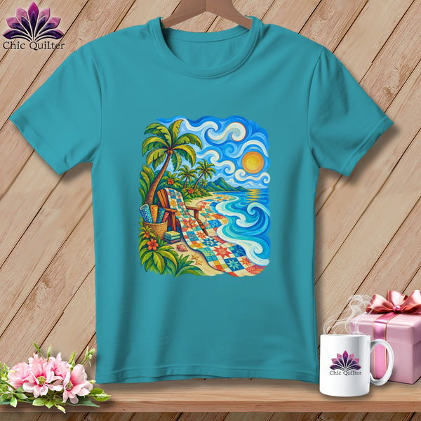 Teal t-shirt hanging on a wooden wall, featuring a colorful beach quilt graphic.
