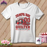 White t-shirt featuring a Tampa Bay Quilter graphic with a pincushion, scissors, and spools of thread.
