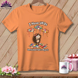 An orange t-shirt displays a cartoon hedgehog surrounded by quilting scraps and flying UFO-shaped patchwork quilts.