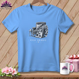 Light blue t-shirt with a drawing of a chair, quilt, and mug, reading 
