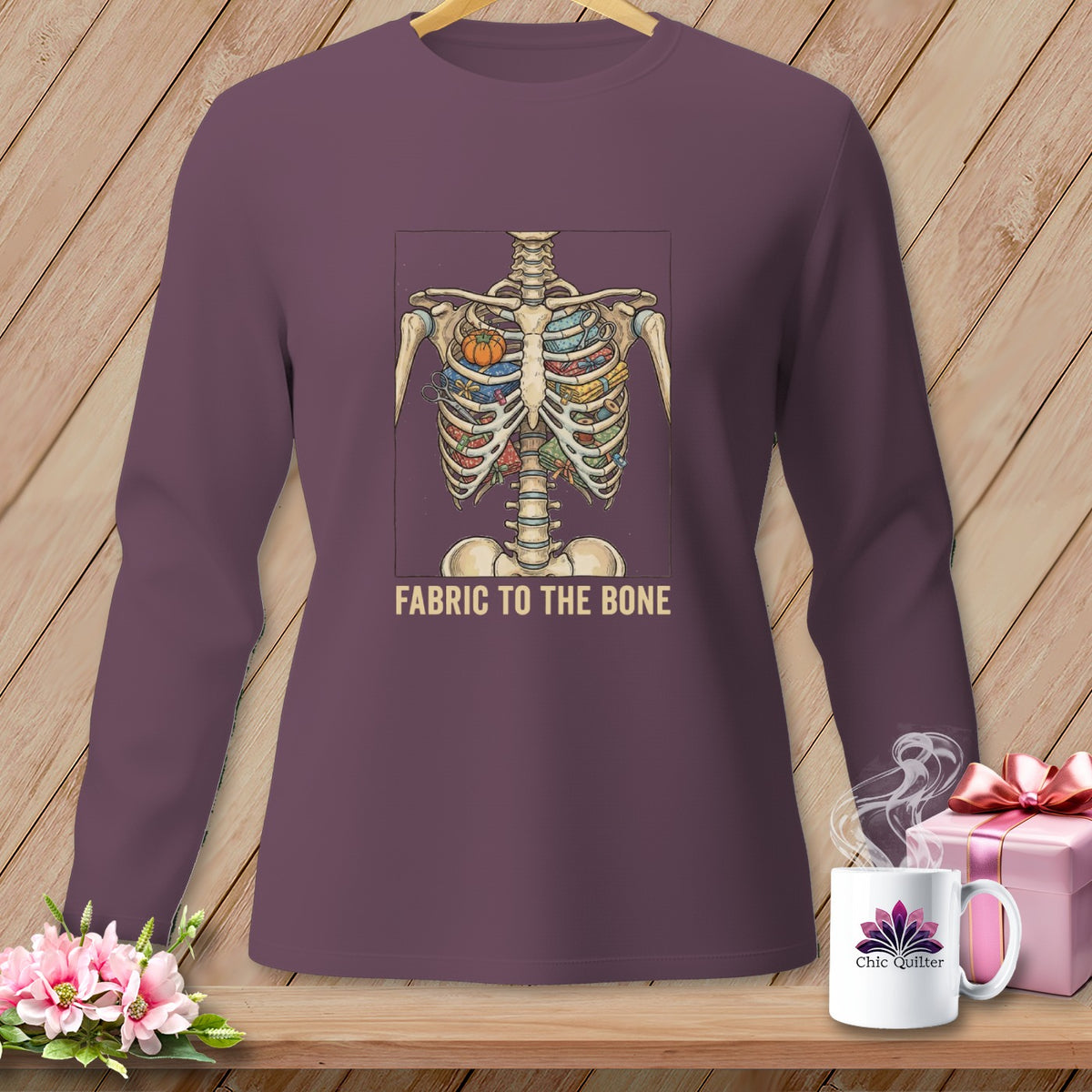 Long-sleeve shirt with skeleton ribcage filled with fabric, scissors, and pumpkin, text "FABRIC TO THE BONE".