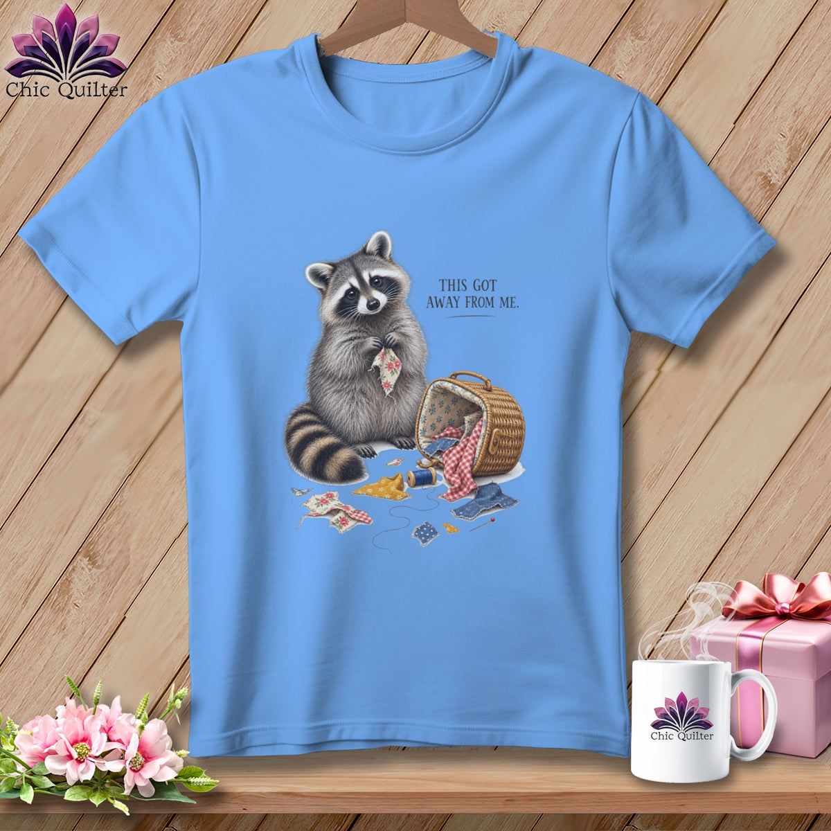 Light blue t-shirt with a raccoon and sewing supplies, text reads "THIS GOT AWAY FROM ME."