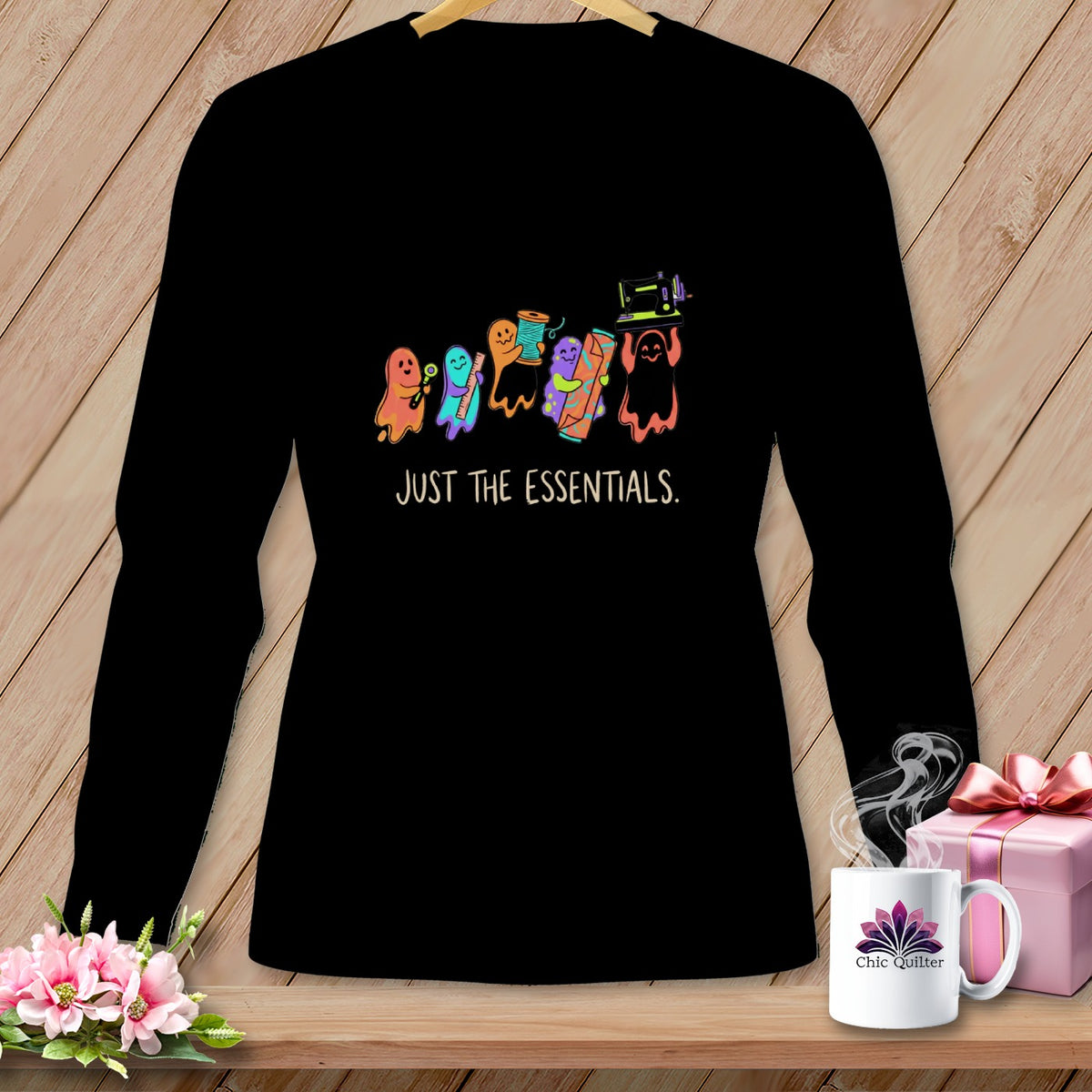 Black long-sleeve shirt with cartoon ghosts holding sewing supplies and "JUST THE ESSENTIALS." text.