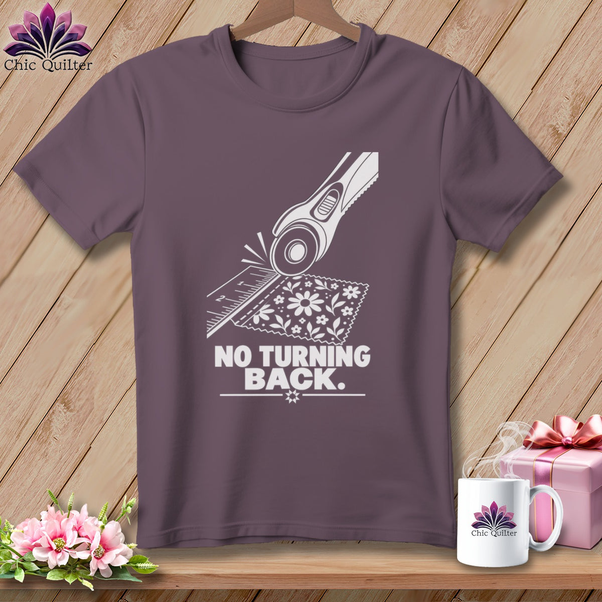 Purple t-shirt with a white graphic of a rotary cutter, ruler, fabric, and the text "NO TURNING BACK."