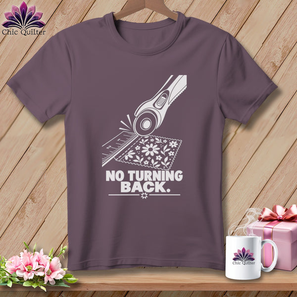 Purple t-shirt with a white graphic of a rotary cutter, ruler, fabric, and the text "NO TURNING BACK."