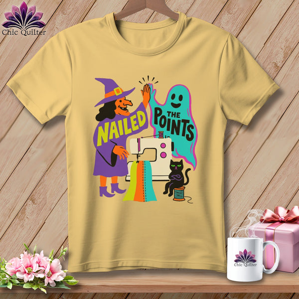 Yellow t-shirt with witch, ghost, sewing machine, cat, and text "Nailed the Points".