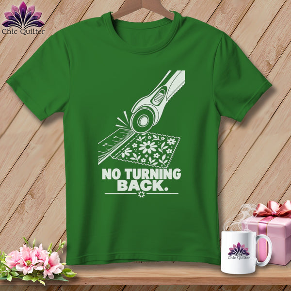 Green t-shirt with white graphic of rotary cutter and fabric, saying "NO TURNING BACK."