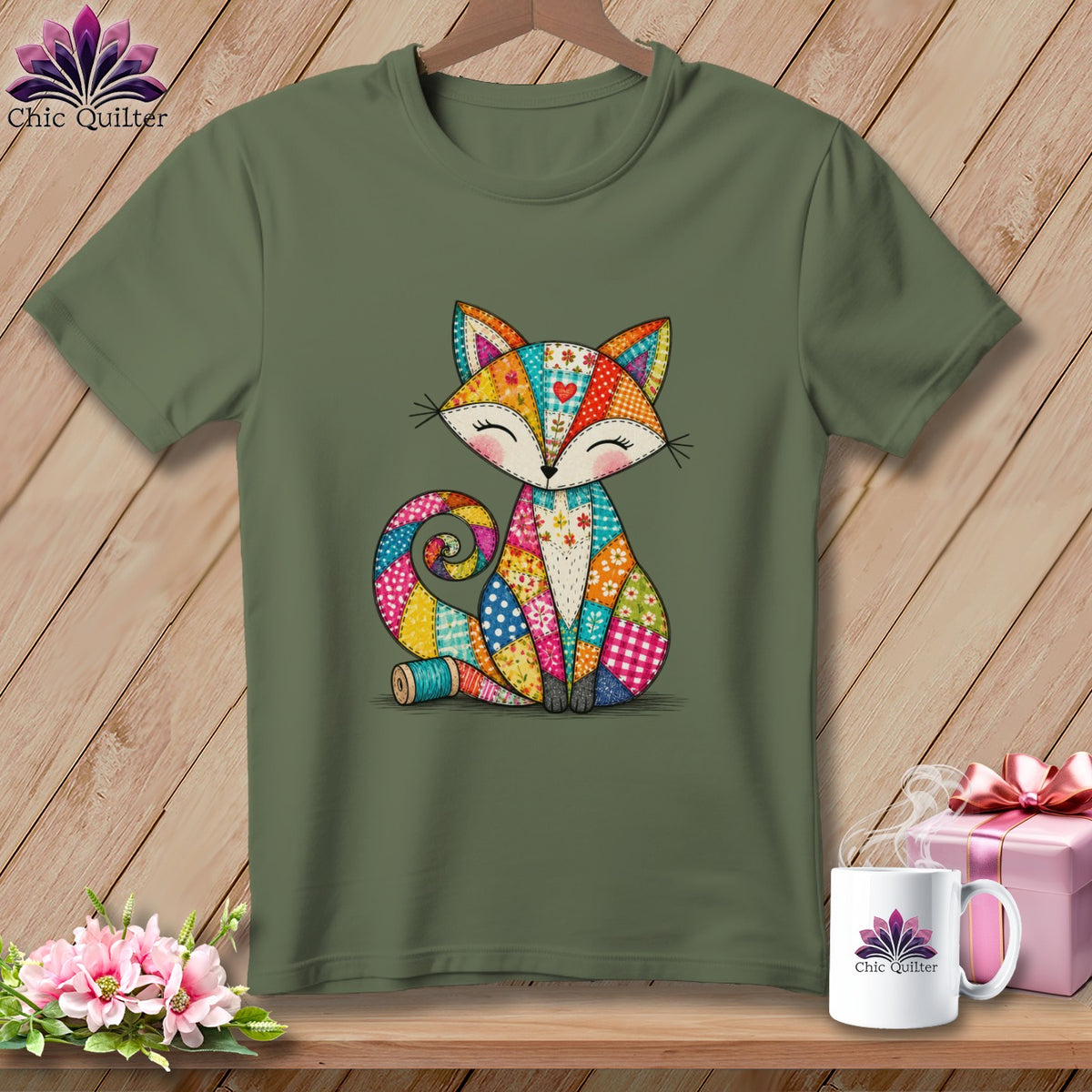 An olive green t-shirt featuring a colorful patchwork fox graphic hanging against a wooden background.