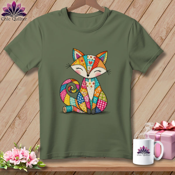 An olive green t-shirt featuring a colorful patchwork fox graphic hanging against a wooden background.