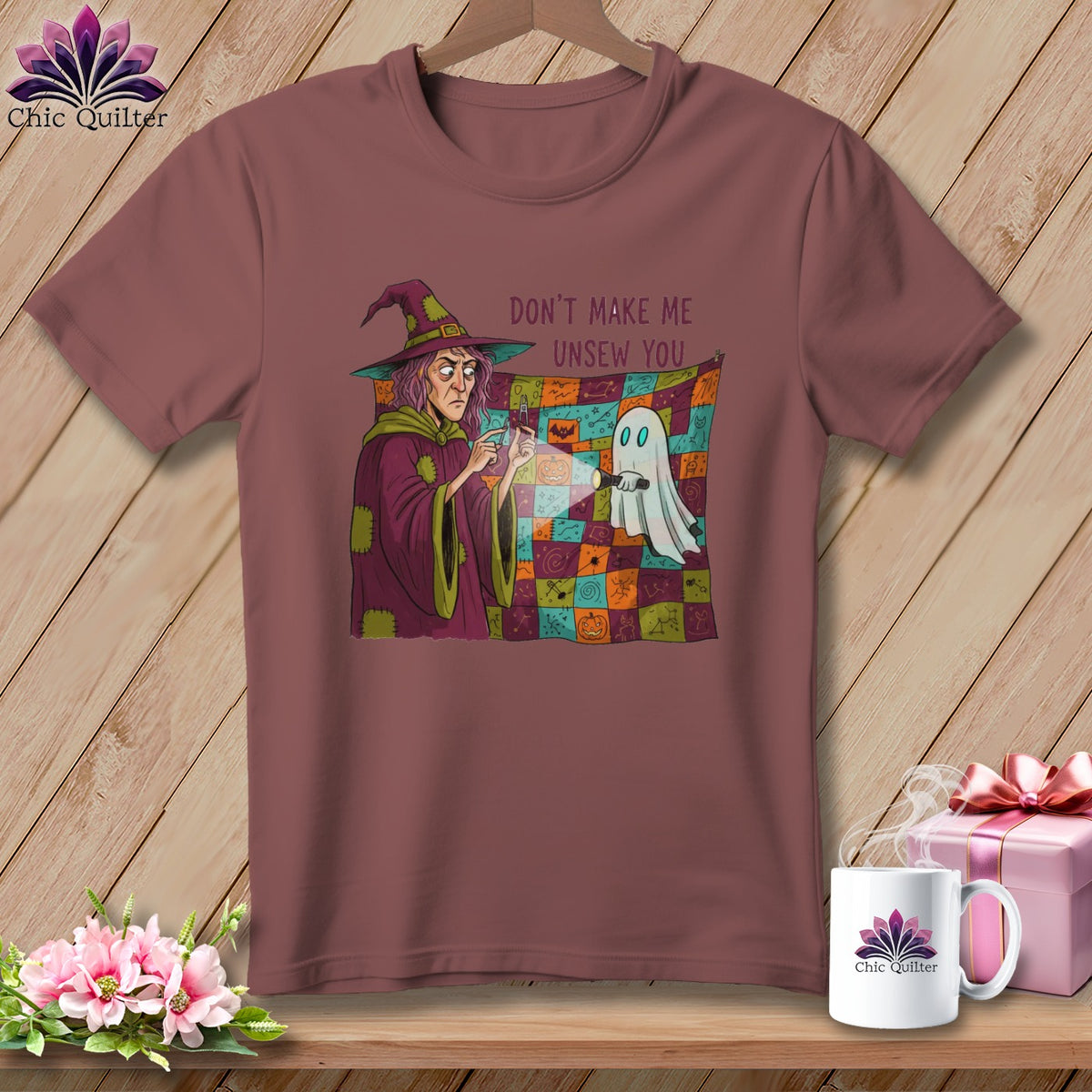 Witch pointing flashlight at ghost with text "Don't make me unsew you" on t-shirt.