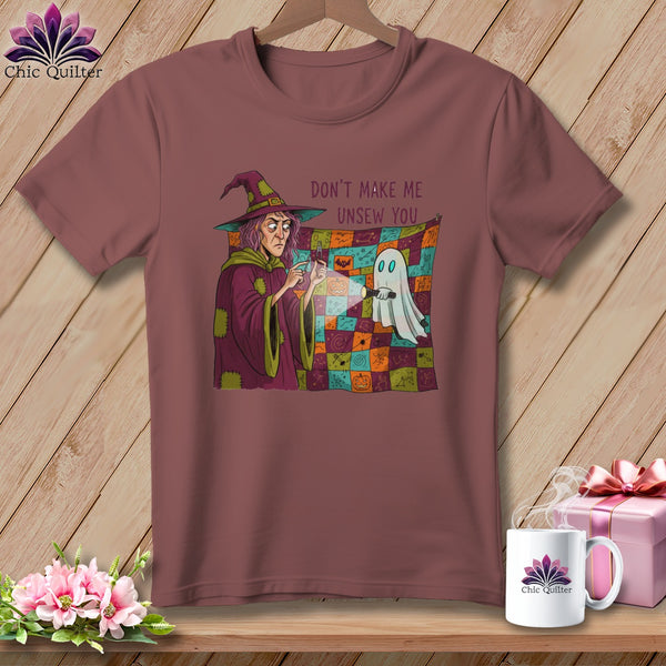 Witch pointing flashlight at ghost with text "Don't make me unsew you" on t-shirt.