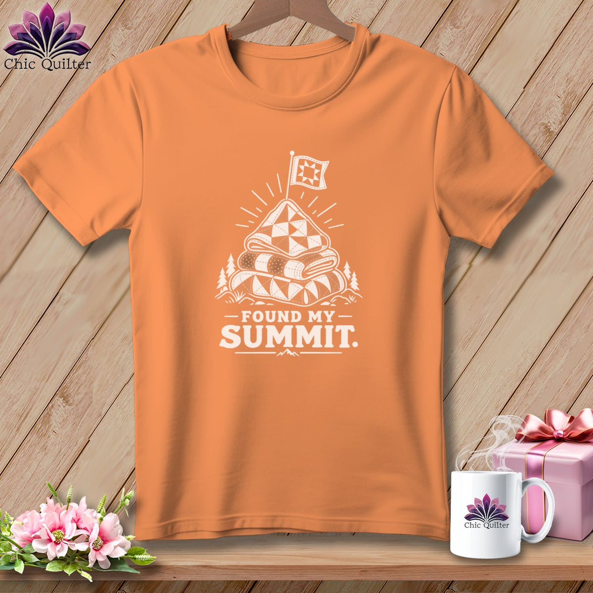 Orange t-shirt with white graphic "Found My Summit" above a quilt on a mountain.