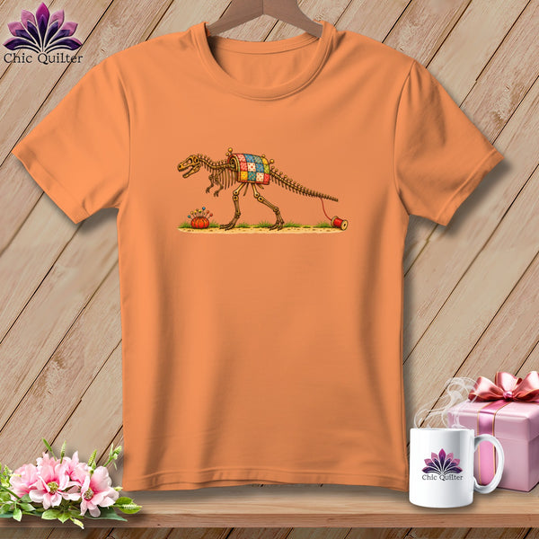 An orange t-shirt displays a graphic of a dinosaur skeleton wearing a patchwork quilt.
