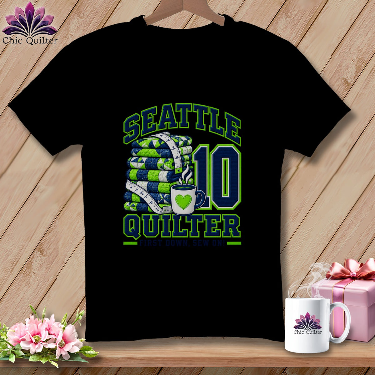 Black t-shirt featuring a Seattle Quilter graphic with folded quilts, a measuring tape, and a coffee mug.