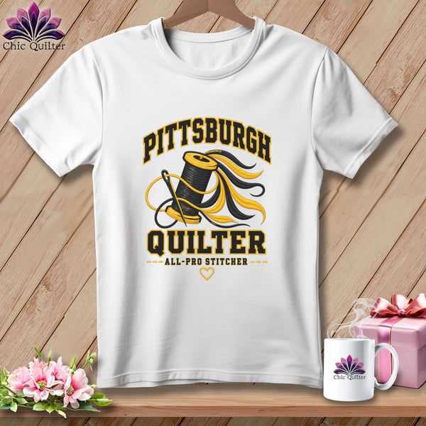 White t-shirt featuring a Pittsburgh Quilter graphic with a spool of thread, needle, and text.
