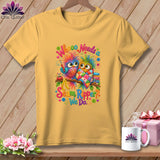 A yellow t-shirt hanging on a wooden background, featuring a colorful owl graphic with quilting text.