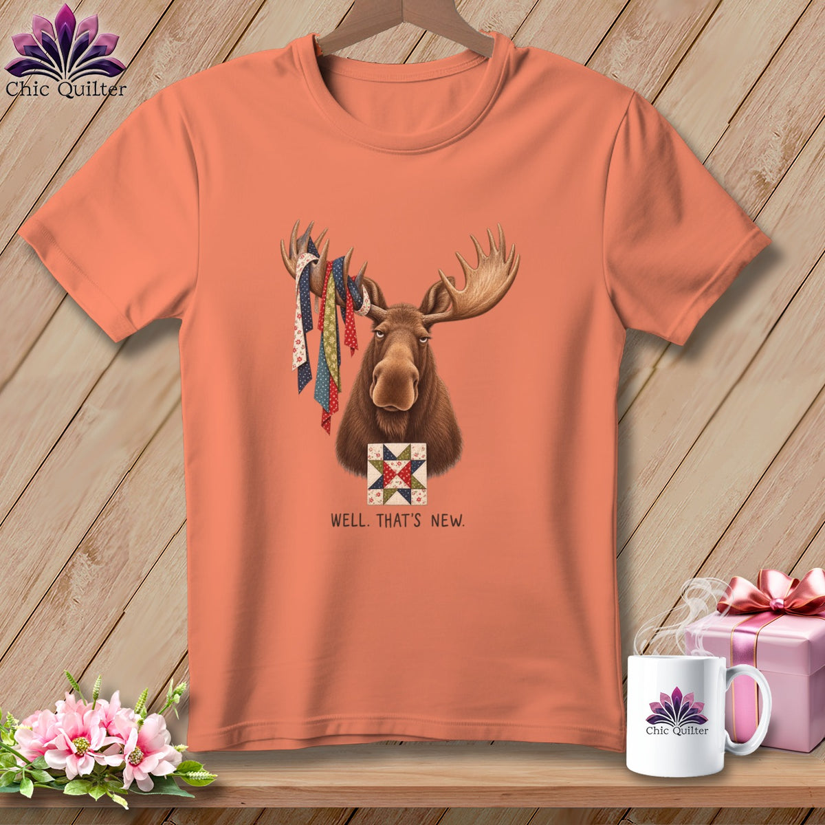 Peach t-shirt with a moose wearing colorful fabric strips and a quilt square.