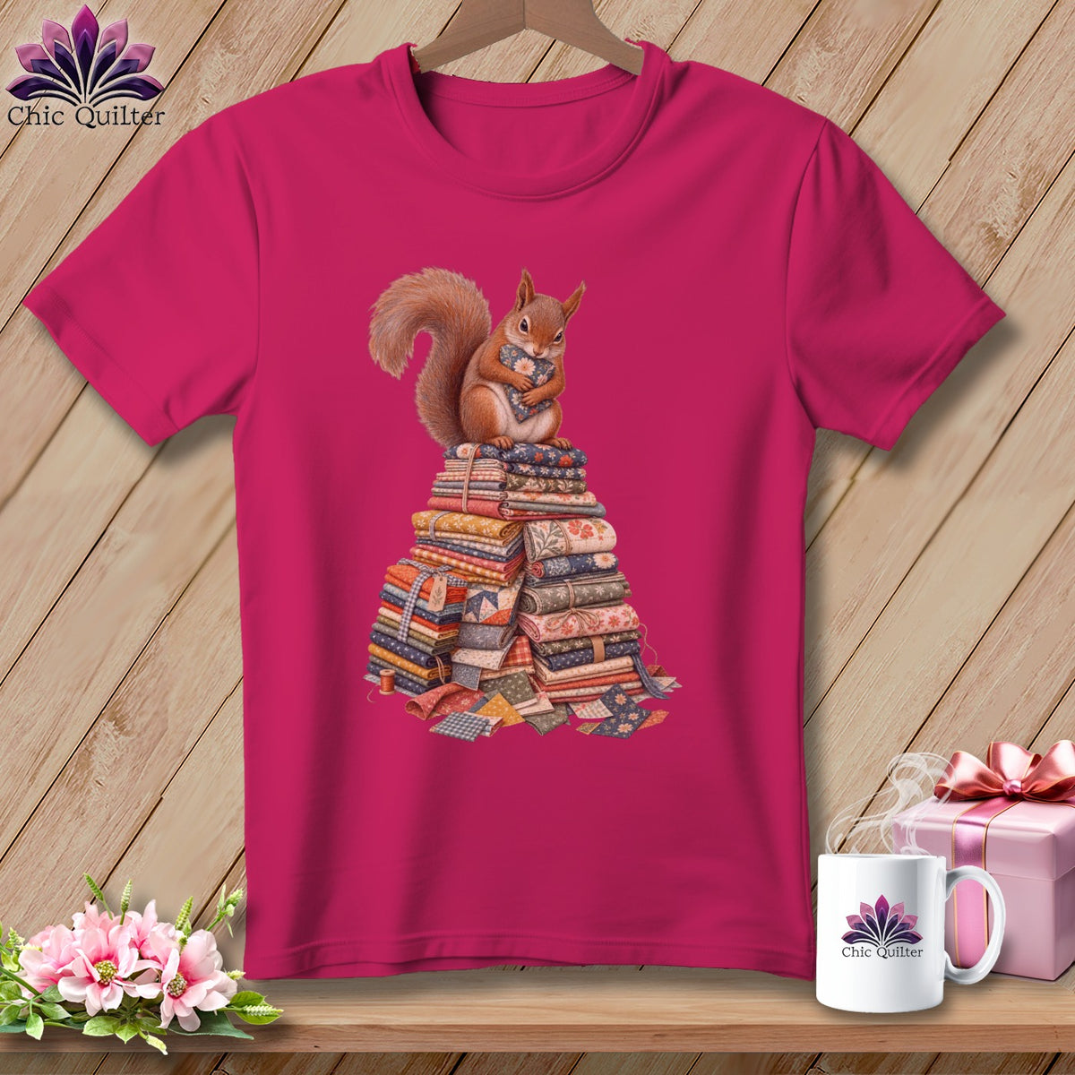 Fuchsia t-shirt with a squirrel holding fabric atop a pile of fabric.