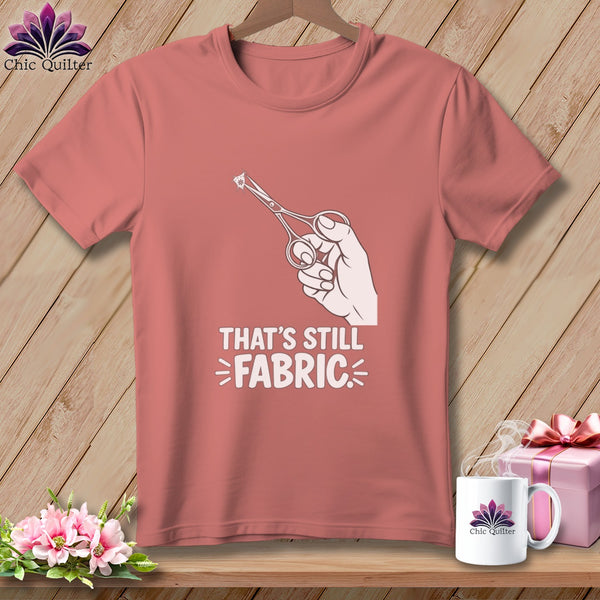 Peach t-shirt with hand holding scissors cutting fabric graphic and text.