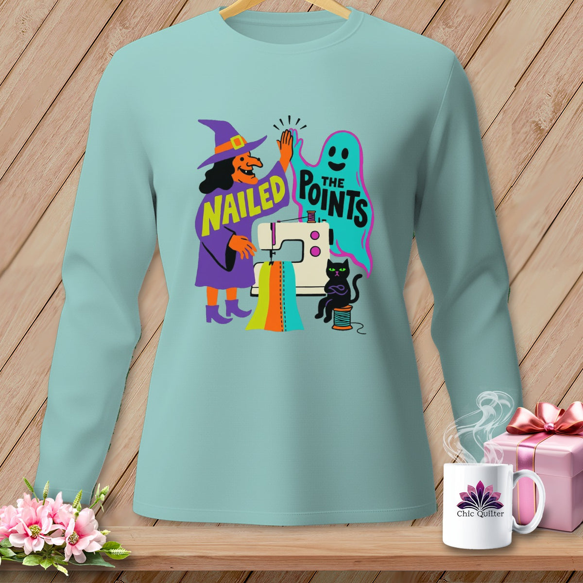 Light blue long sleeve shirt with witch, ghost, sewing machine, and black cat Halloween graphic.
