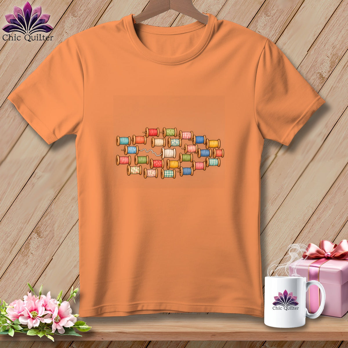 Orange crewneck t-shirt featuring a central graphic of colorful spools of thread.