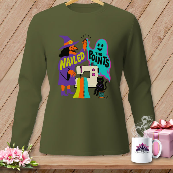 Green long-sleeve shirt with a witch, ghost, sewing machine, and black cat graphic that says "Nailed the Points".