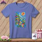 Purple short-sleeve t-shirt with a colorful graphic of sewing supplies, spools, and a patchwork quilt.