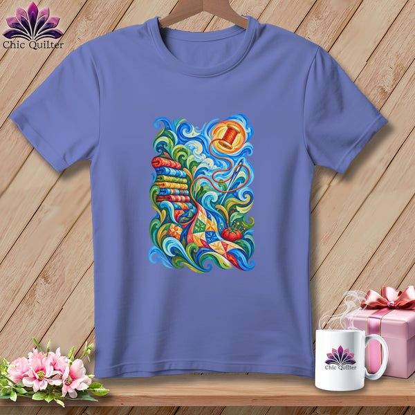Purple short-sleeve t-shirt with a colorful graphic of sewing supplies, spools, and a patchwork quilt.