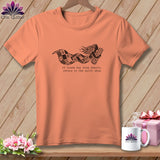Peach t-shirt with a graphic of a woman holding fabric and the text 