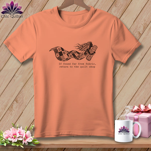 Peach t-shirt with a graphic of a woman holding fabric and the text "If found far from fabric, return to the quilt shop."