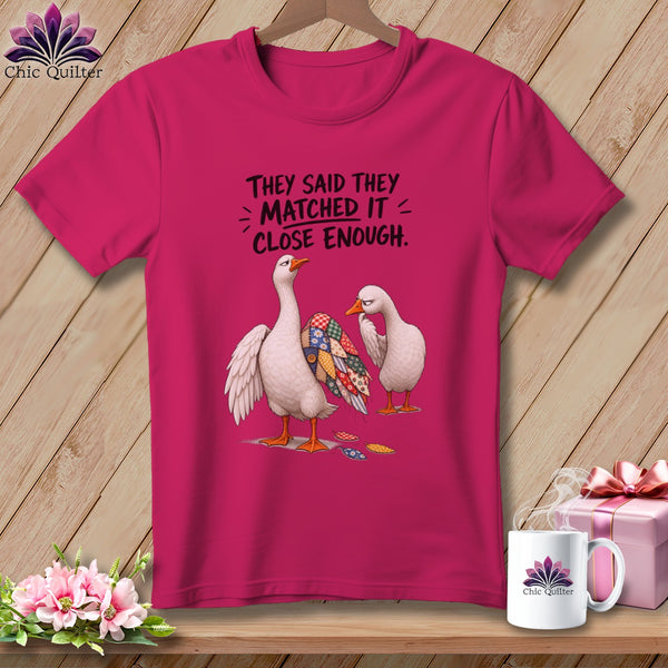 Pink t-shirt with two geese, one with a patchwork quilt pattern, and text.