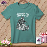 Teal t-shirt featuring a black-and-white graphic of a bear and raccoon quilting, with text reading 
