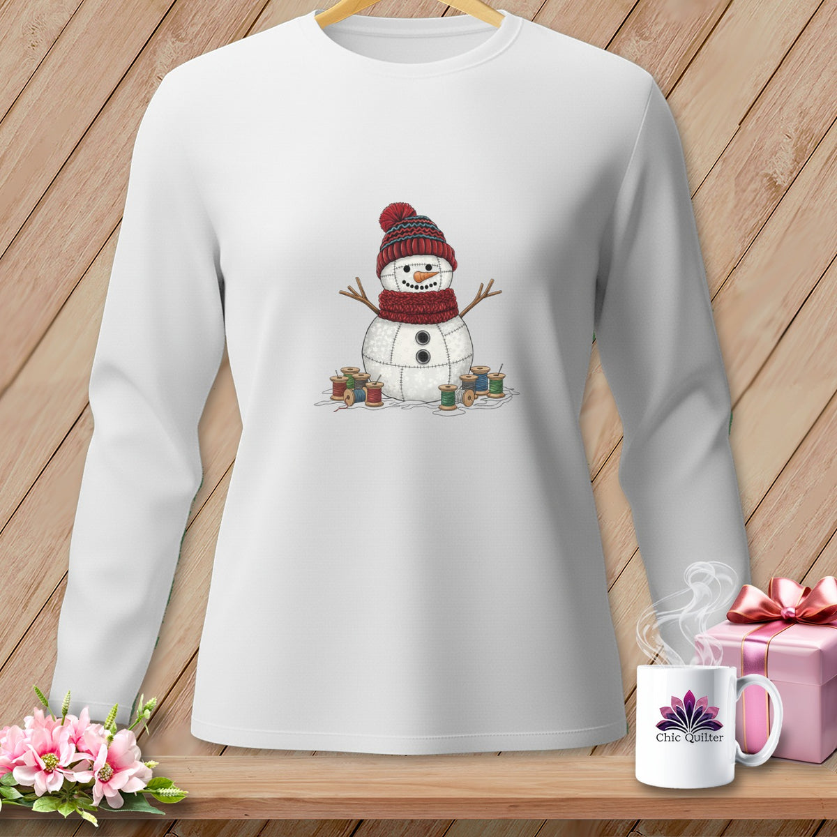 White long-sleeved shirt with a stitched snowman graphic surrounded by spools of thread.