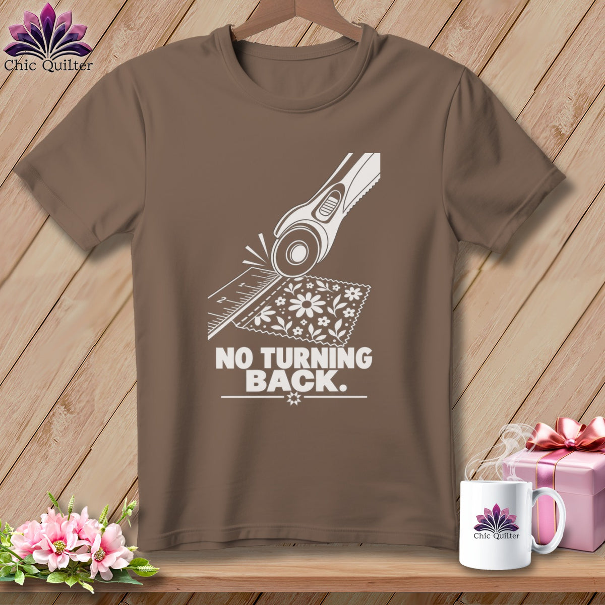 Brown t-shirt with white graphic of rotary cutter, ruler, fabric, and text "NO TURNING BACK."