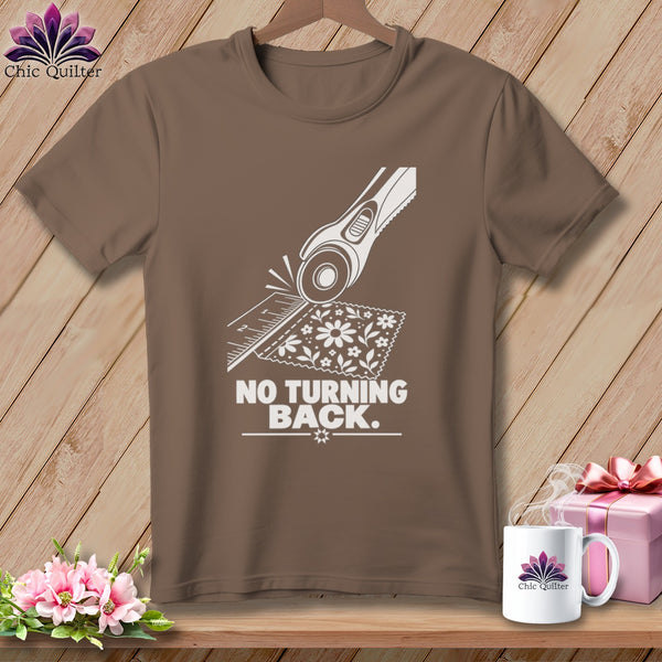 Brown t-shirt with white graphic of rotary cutter, ruler, fabric, and text "NO TURNING BACK."