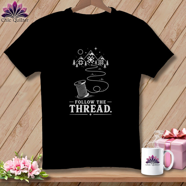 Black t-shirt with "Follow The Thread" text and sewing spool design.