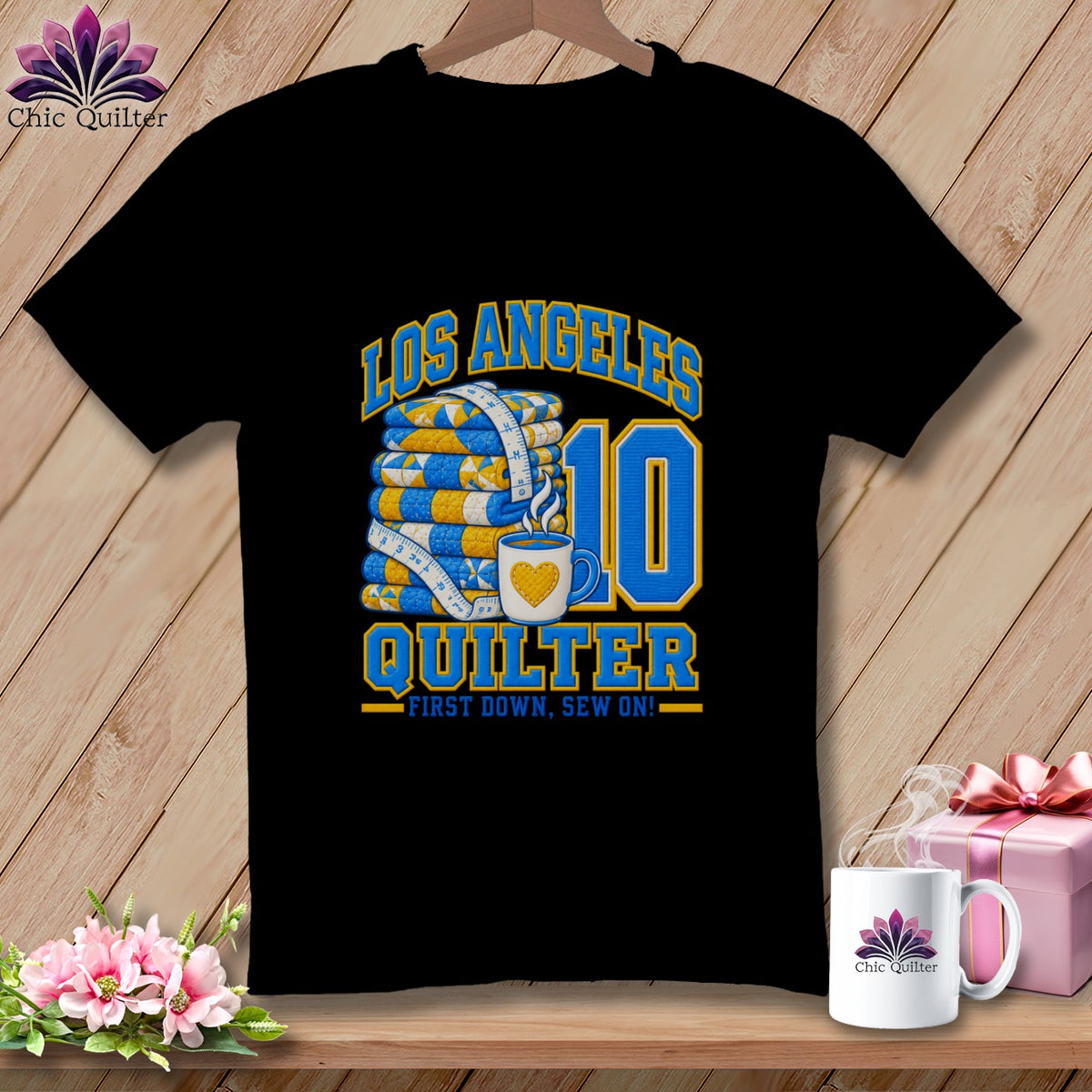 Black t-shirt featuring Los Angeles Quilter graphic with folded quilts, measuring tape, coffee mug, and number ten.