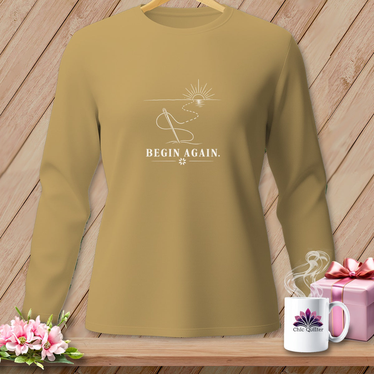 Long-sleeved shirt with "BEGIN AGAIN" text and sewing needle design.