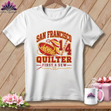 A white t-shirt features a San Francisco Quilter graphic with a basket of buttons and needles.