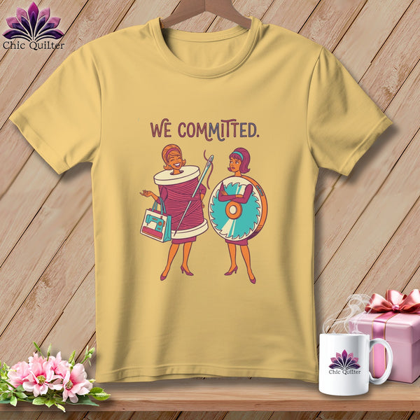 T-shirt with cartoon women, spool of thread, sewing machine bag, and rotary cutter, saying "We Committed."