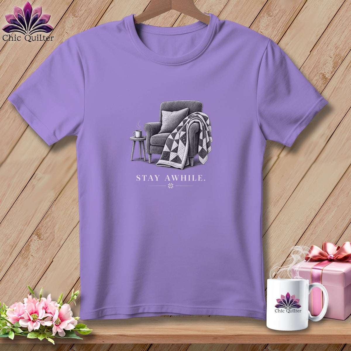 Purple t-shirt with an illustration of a chair, quilt, and text "STAY AWHILE."