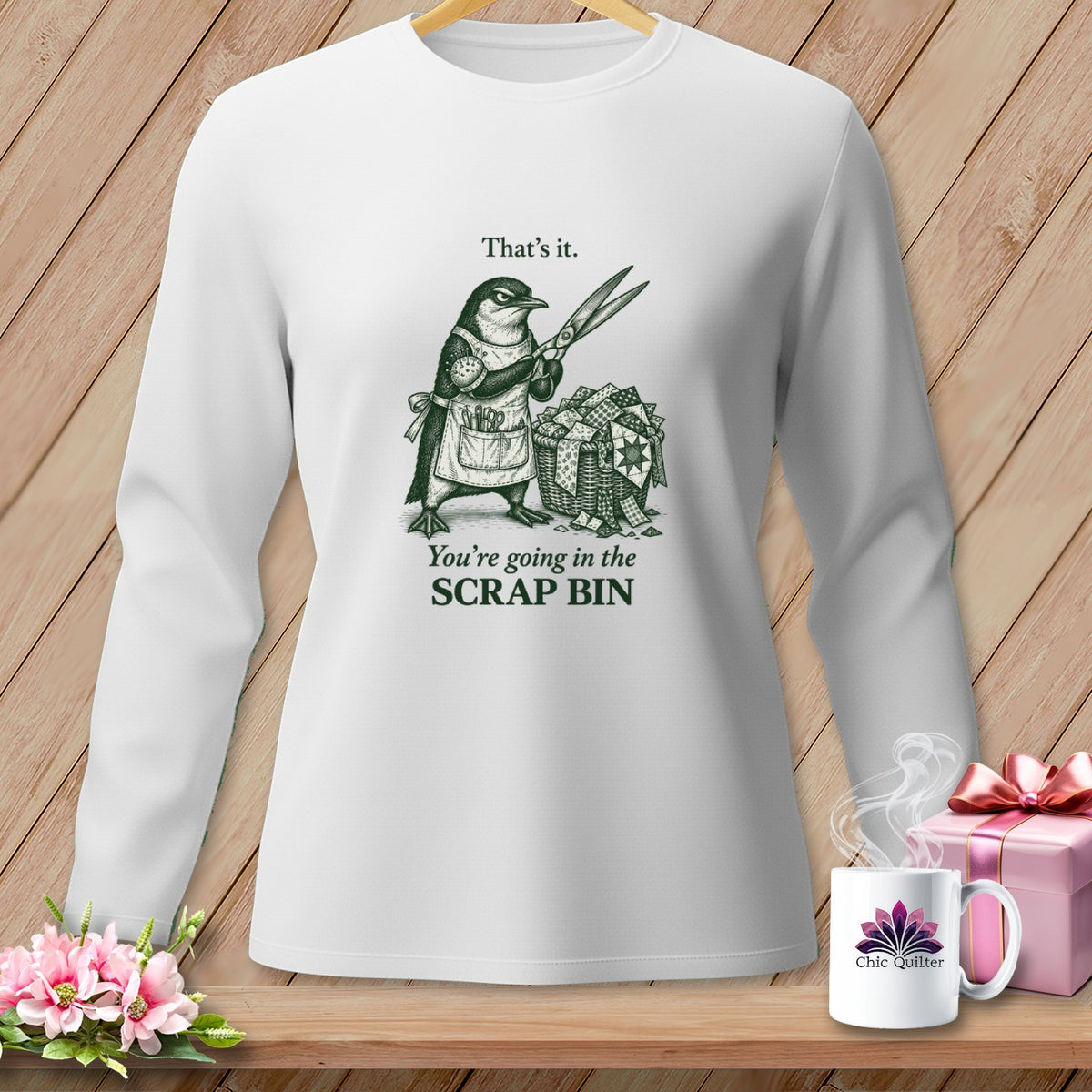 White long-sleeve shirt with a penguin holding scissors above a scrap basket.