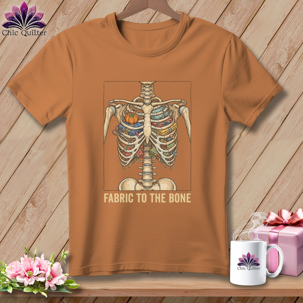 Orange t-shirt with skeleton rib cage filled with fabric and sewing notions, text reads "Fabric to the bone".