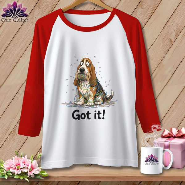 White raglan shirt with red sleeves featuring a basset hound tangled in colorful yarn and text "Got it!".