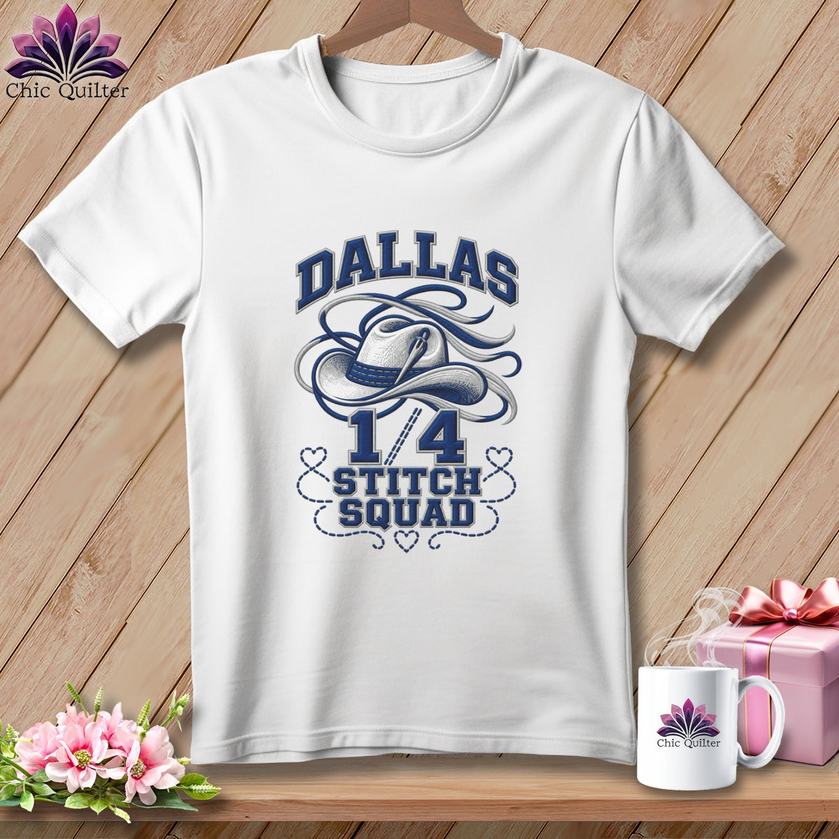 White t-shirt hanging on a wooden background, featuring blue text that reads Dallas 1/4 Stitch Squad and a cowboy hat graphic.