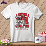 A white t-shirt features a graphic with a crate of fabric rolls and text reading Arizona Quilter.