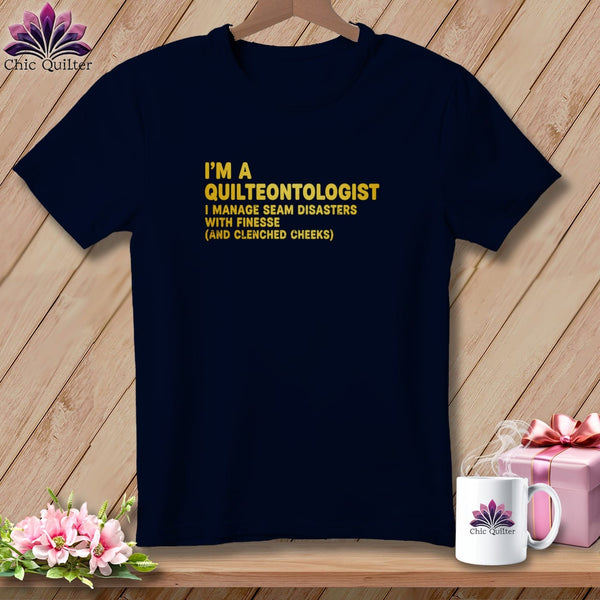 Navy t-shirt with gold text "I'm a Quilteontologist" and "I manage seam disasters with finesse (and clenched cheeks)".